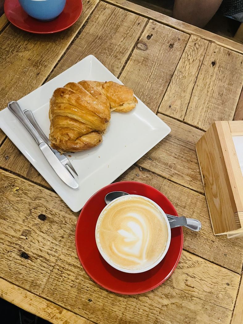 Croissant de mantequilla recién horneado acompañado de un café.